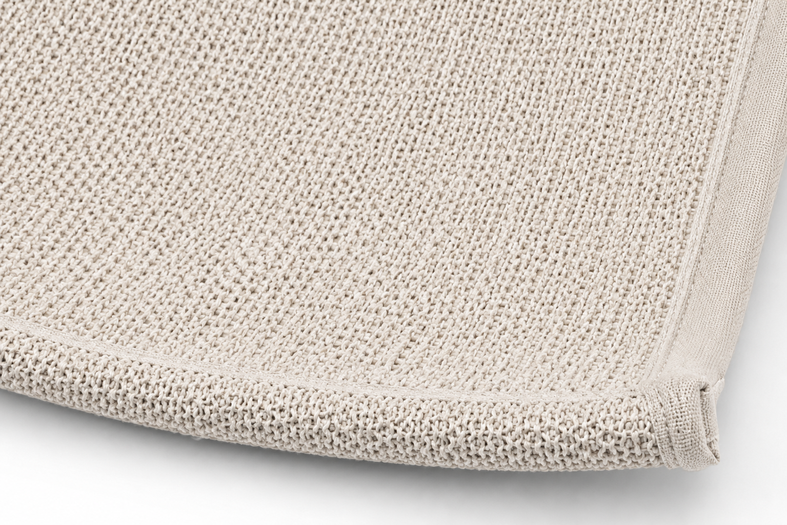 Close-up view of a neatly folded, light beige, textured bath towel edge