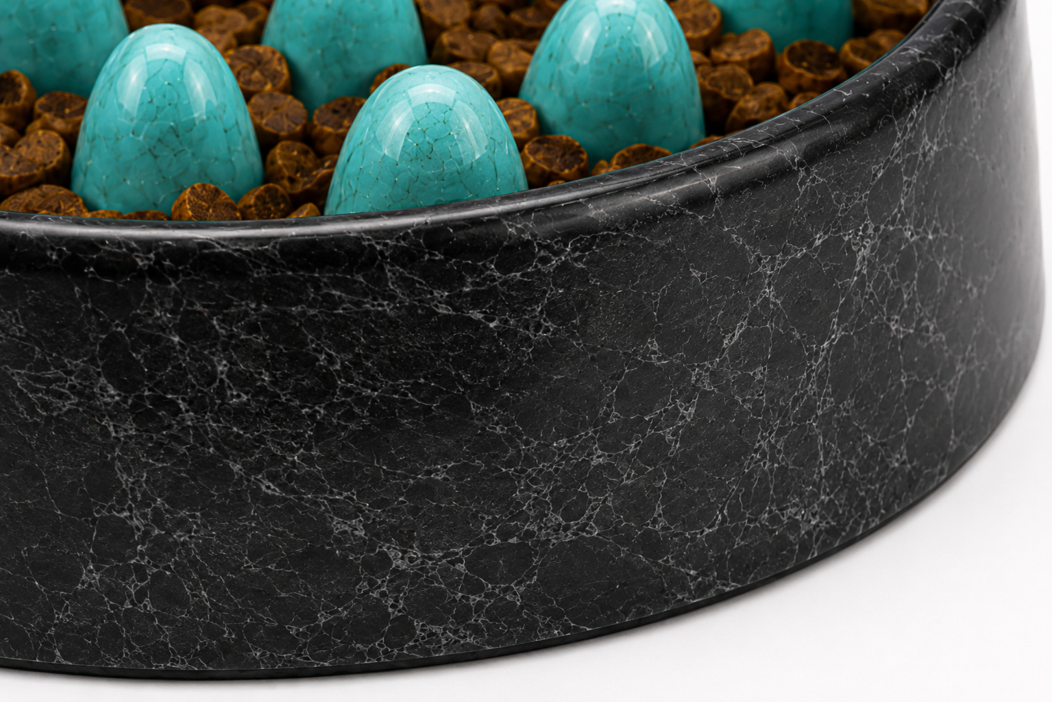 Black marble bowl filled with turquoise eggs on a brown speckled base